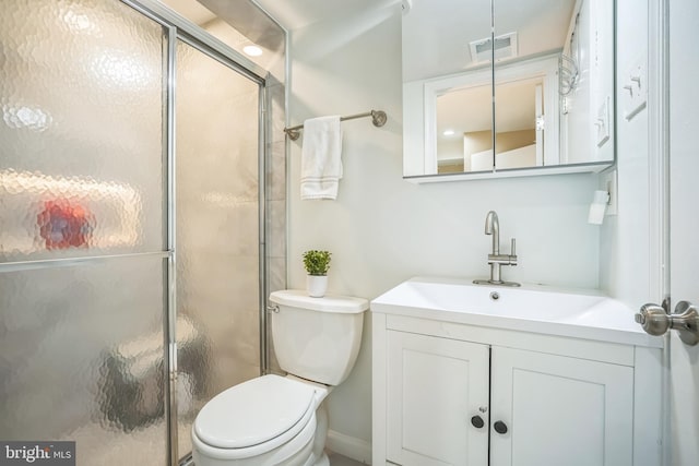 bathroom with vanity, a shower stall, toilet, and visible vents