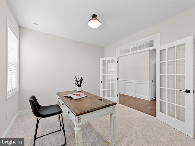 office area with a wainscoted wall, plenty of natural light, french doors, and carpet flooring