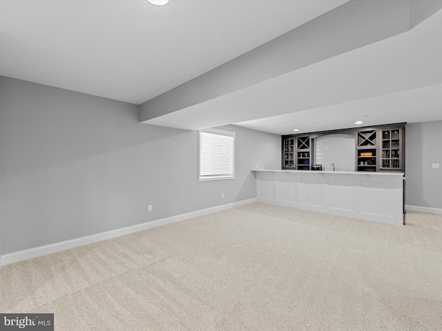 basement with baseboards, recessed lighting, wet bar, and light colored carpet