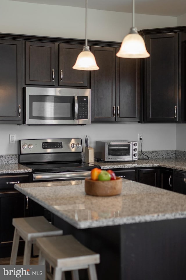 kitchen with pendant lighting, a toaster, a kitchen bar, and stainless steel appliances