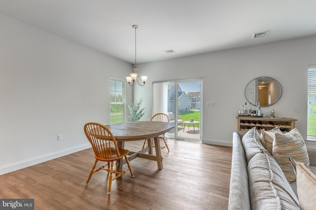 dining room with visible vents, wood finished floors, and an inviting chandelier