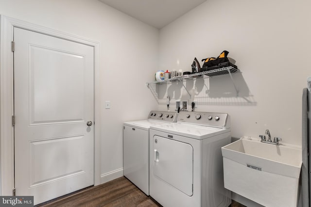 laundry room with laundry area, washing machine and clothes dryer, a sink, baseboards, and dark wood-style floors
