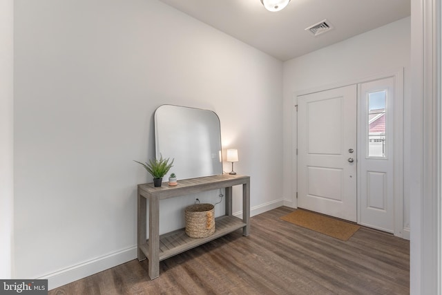 foyer entrance featuring baseboards, visible vents, and wood finished floors