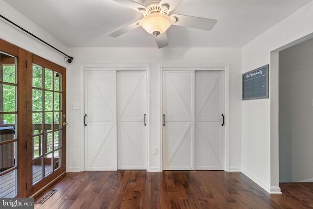 interior space with a ceiling fan, visible vents, baseboards, dark wood-style floors, and multiple closets