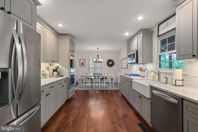 kitchen with gray cabinetry, appliances with stainless steel finishes, decorative backsplash, and a sink