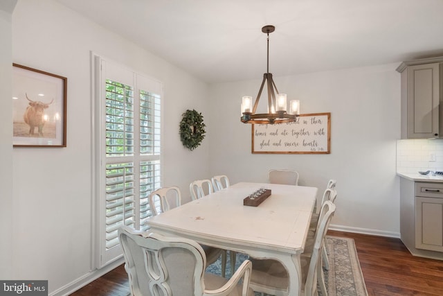dining area with baseboards, a notable chandelier, and dark wood-style floors