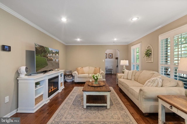 living room with arched walkways, dark wood finished floors, baseboards, ornamental molding, and recessed lighting