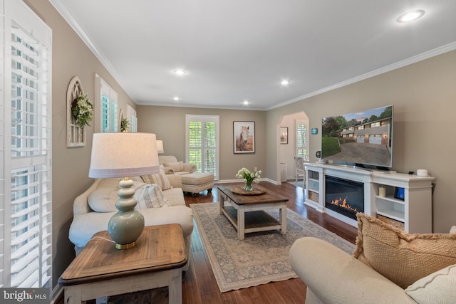 living area with crown molding, wood finished floors, baseboards, recessed lighting, and arched walkways