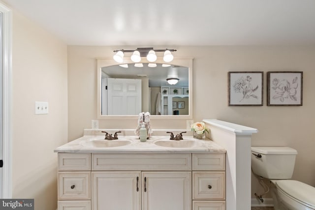 bathroom with double vanity, toilet, and a sink