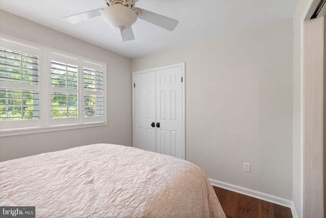 bedroom featuring a closet, a ceiling fan, dark wood-style flooring, and baseboards