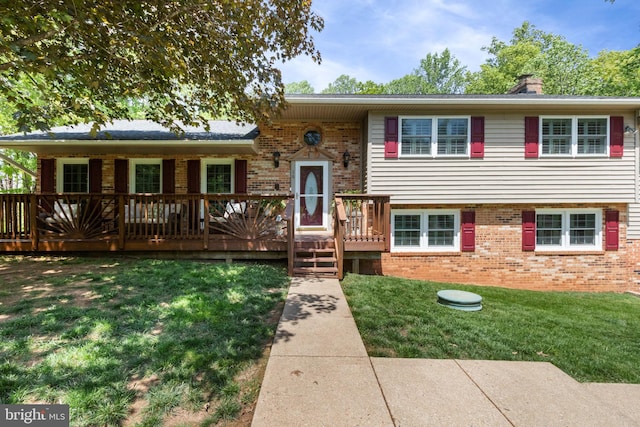view of front of property featuring brick siding, a chimney, a front yard, and a deck
