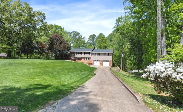split foyer home with a garage, a front yard, brick siding, and aphalt driveway