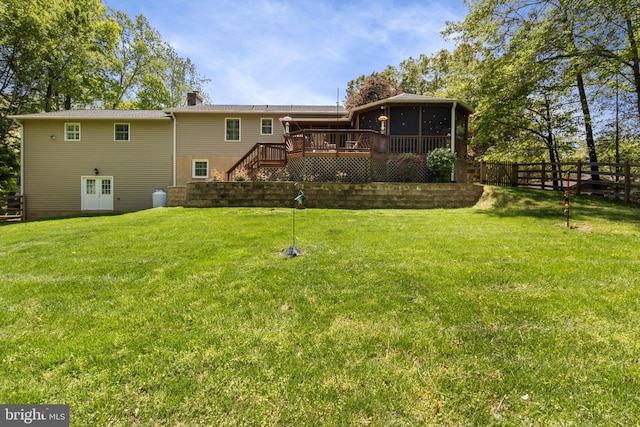 rear view of house with fence, a wooden deck, a sunroom, stairway, and a yard