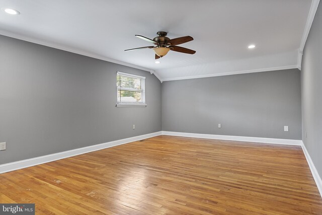 spare room with light wood-style floors, a ceiling fan, baseboards, vaulted ceiling, and ornamental molding