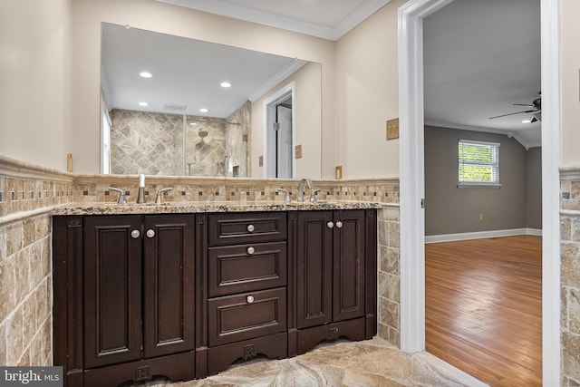 bathroom featuring crown molding, wood finished floors, ceiling fan, tiled shower, and a sink
