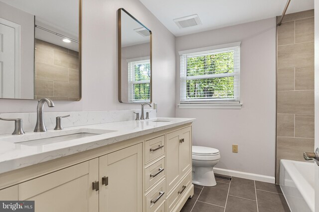 bathroom featuring double vanity, toilet, a sink, and tile patterned flooring