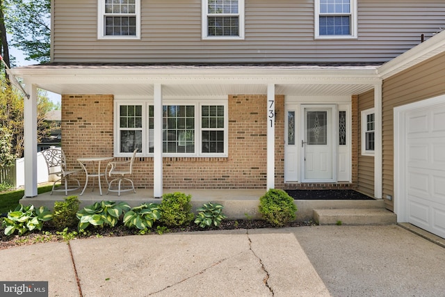 property entrance featuring covered porch and brick siding