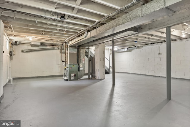 unfinished below grade area featuring heating unit and stairway