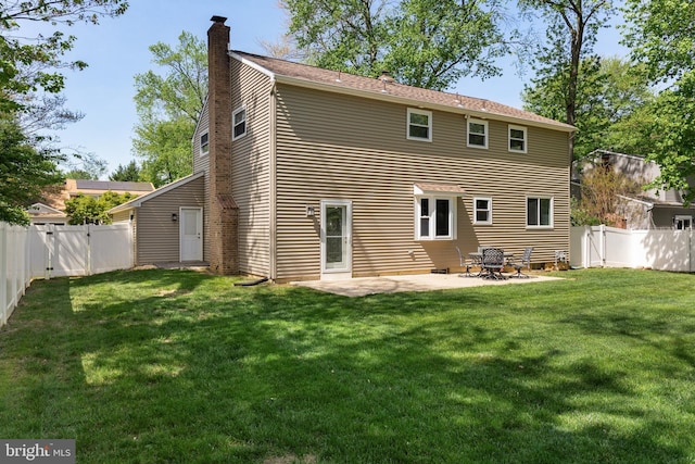 rear view of house with a lawn, a chimney, and a patio area