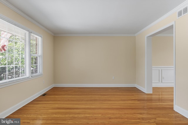 unfurnished room featuring baseboards, visible vents, ornamental molding, and light wood-type flooring