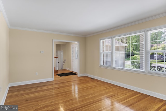 empty room with baseboards, ornamental molding, and light wood-type flooring