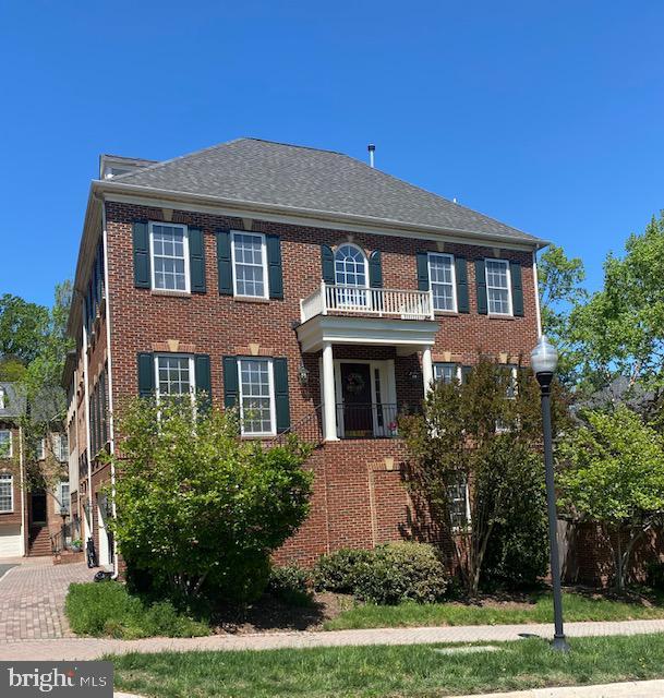 colonial inspired home with brick siding and a balcony