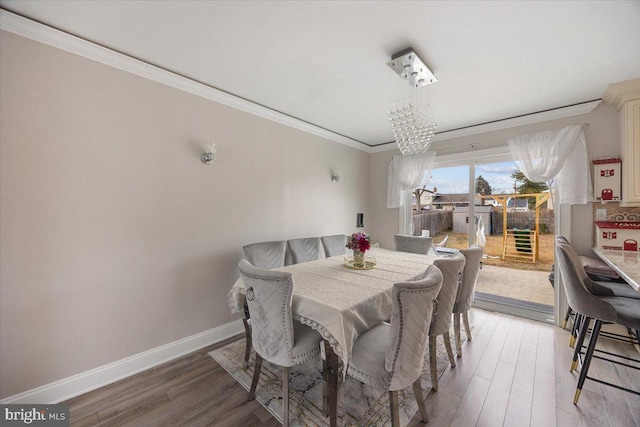 dining area with baseboards, ornamental molding, light wood-type flooring, and a chandelier