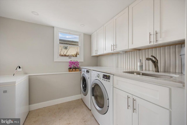 clothes washing area with a sink, baseboards, cabinet space, and independent washer and dryer