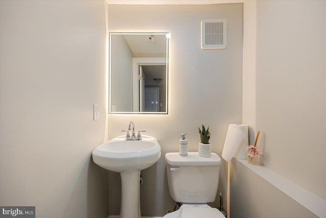 bathroom featuring toilet, visible vents, and a sink