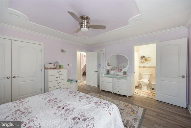 bedroom featuring a tray ceiling, visible vents, ornamental molding, and wood finished floors