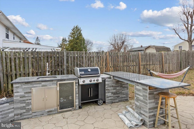view of patio / terrace featuring a fenced backyard, a sink, outdoor dry bar, and area for grilling