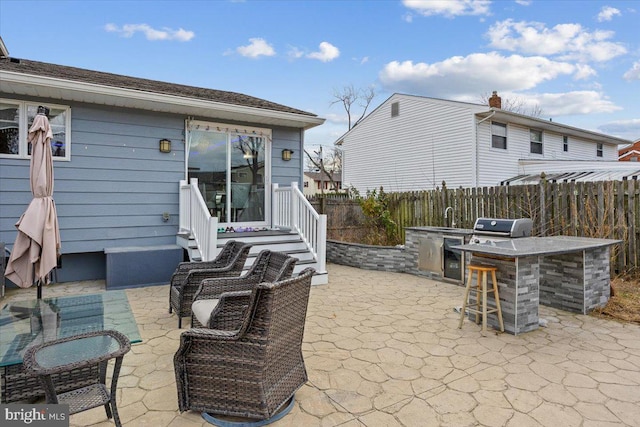 view of patio with fence, outdoor dry bar, exterior kitchen, and area for grilling