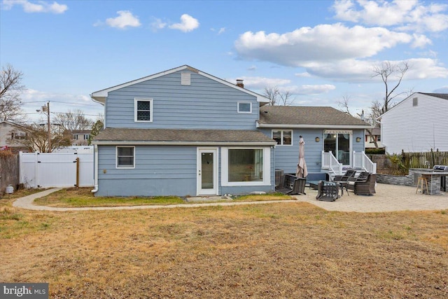 rear view of property with roof with shingles, a gate, a fenced backyard, a yard, and a patio