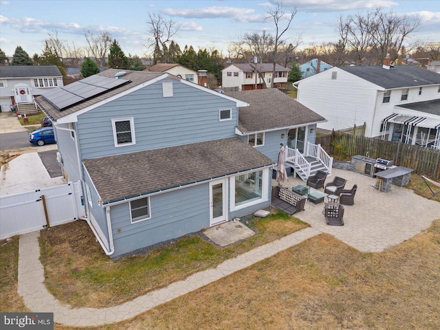 rear view of house featuring a residential view, a shingled roof, a fenced backyard, a gate, and a patio