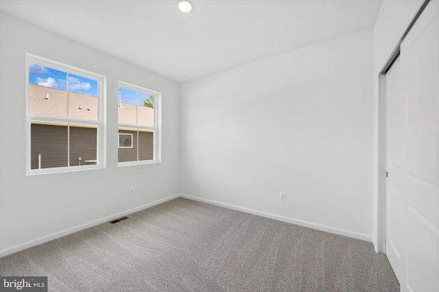 unfurnished bedroom with baseboards, carpet, a closet, and visible vents