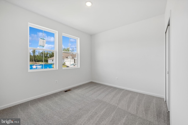 carpeted spare room featuring baseboards and visible vents