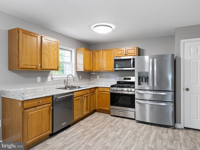 34 Dovetree Dr, Newark, DE 19713 - kitchen featuring appliances with stainless steel finishes, a sink, light countertops, light wood finished floors, and brown cabinets