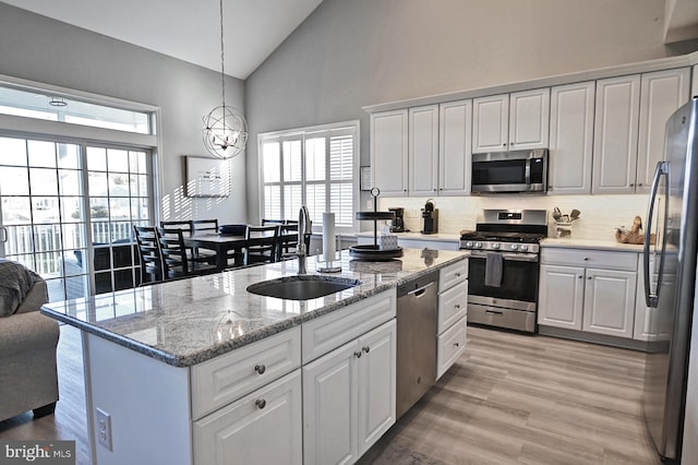 kitchen featuring a sink, high vaulted ceiling, light wood-style flooring, stainless steel appliances, and white cabinetry