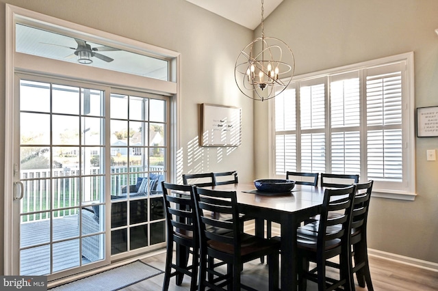 dining room featuring light wood-type flooring, baseboards, ceiling fan with notable chandelier, and lofted ceiling