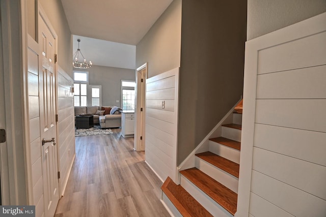 corridor featuring stairway, wood finished floors, and a chandelier