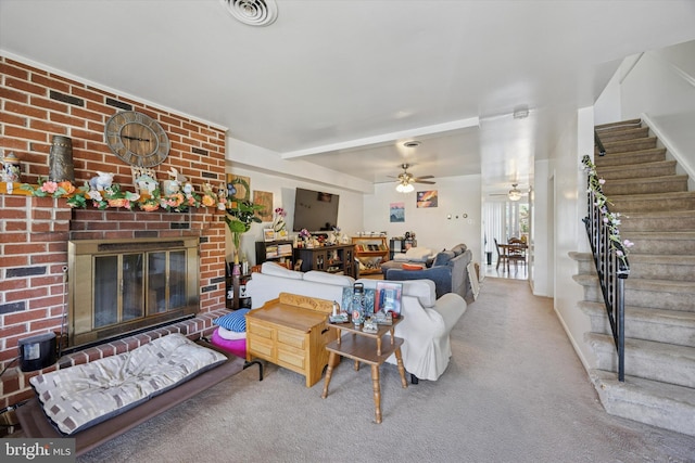 living room featuring carpet flooring, a brick fireplace, a ceiling fan, visible vents, and stairway