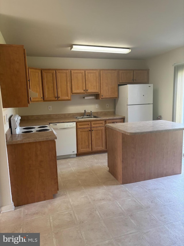 kitchen with a kitchen island, white appliances, light countertops, brown cabinets, and a sink