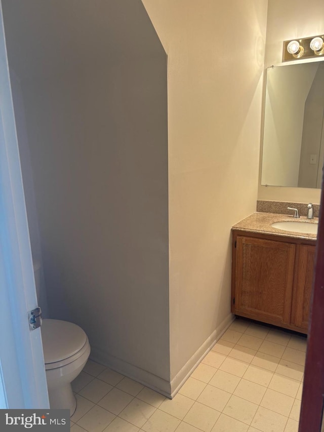 half bath featuring vanity, tile patterned flooring, baseboards, and toilet