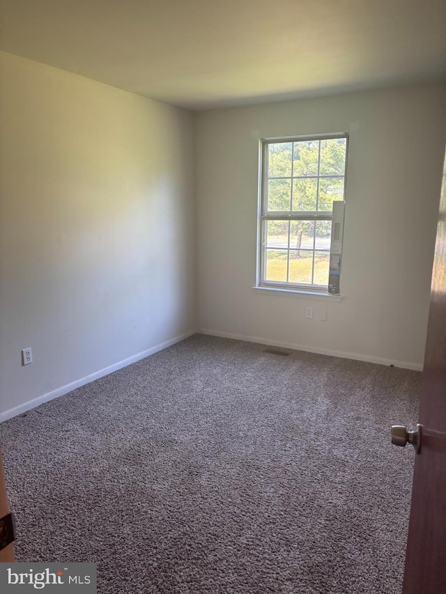 carpeted empty room featuring baseboards and visible vents