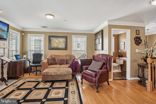 living area with visible vents, ornamental molding, a wealth of natural light, and light wood-type flooring