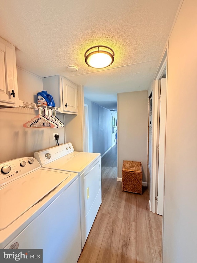 38 Clara St, Norristown, PA 19403 - laundry area featuring light wood-type flooring, washer and dryer, cabinet space, and a textured ceiling