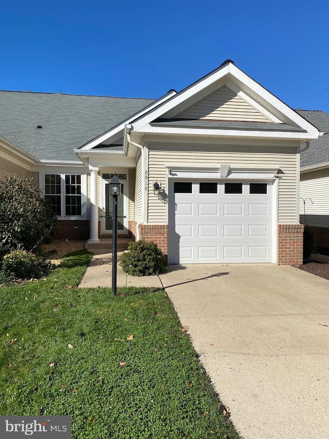 view of front facade featuring concrete driveway, brick siding, a front yard, and a garage