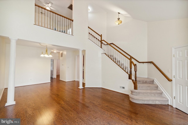 interior space featuring a high ceiling, ceiling fan with notable chandelier, stairs, wood finished floors, and visible vents