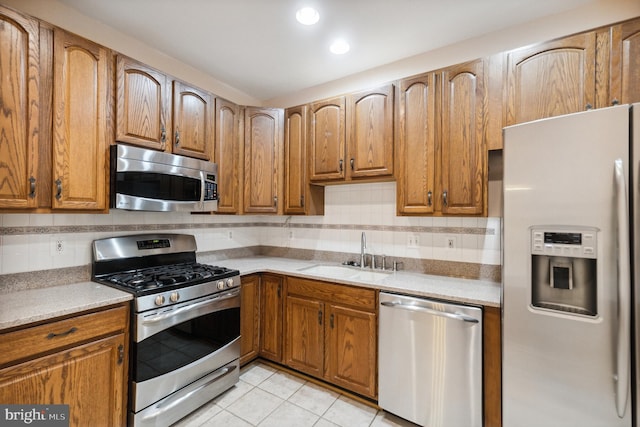 kitchen featuring stainless steel appliances, light tile patterned flooring, a sink, and tasteful backsplash