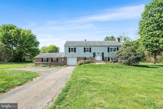 split foyer home with a front lawn, a chimney, brick siding, an attached garage, and driveway